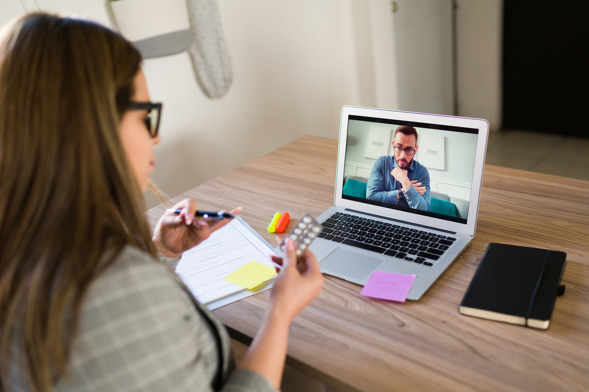 Female psychiatrist giving a medical prescription pills and antidepressants to a depressed male patient during a video call